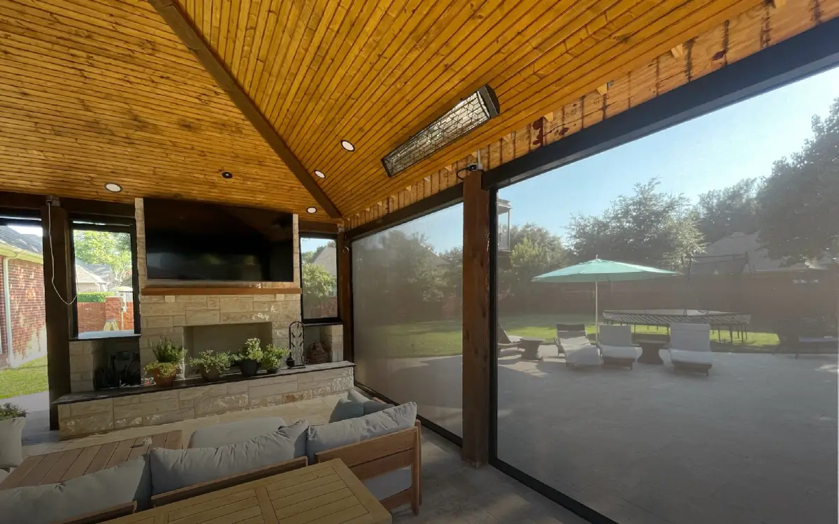 Covered outdoor living room with motorized shades, infrared heater, and wall-mounted TV